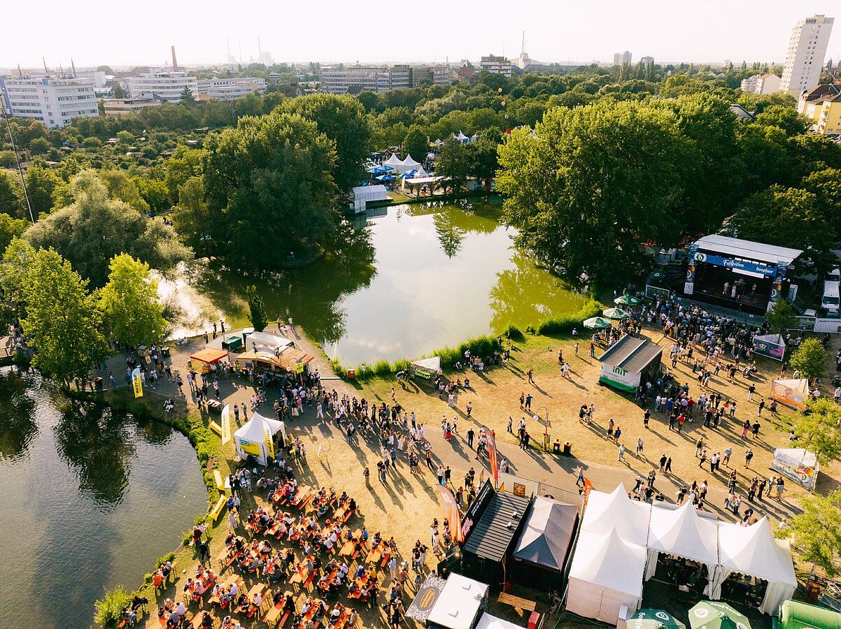 Luftaufnahme des Festivalgeländes am See mit Bühne und Publikum