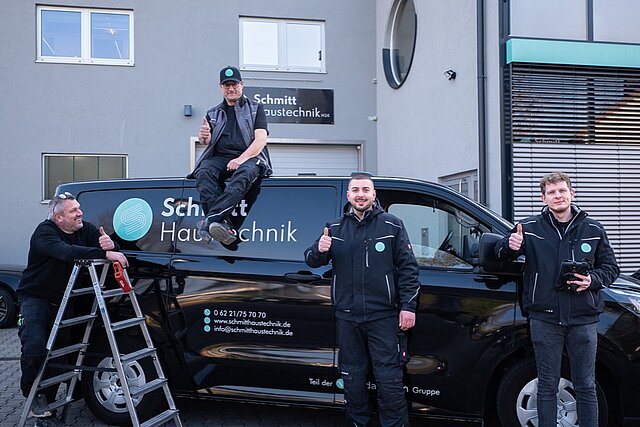 Team von Schmitt Haustechnik posiert vor dem Firmenwagen